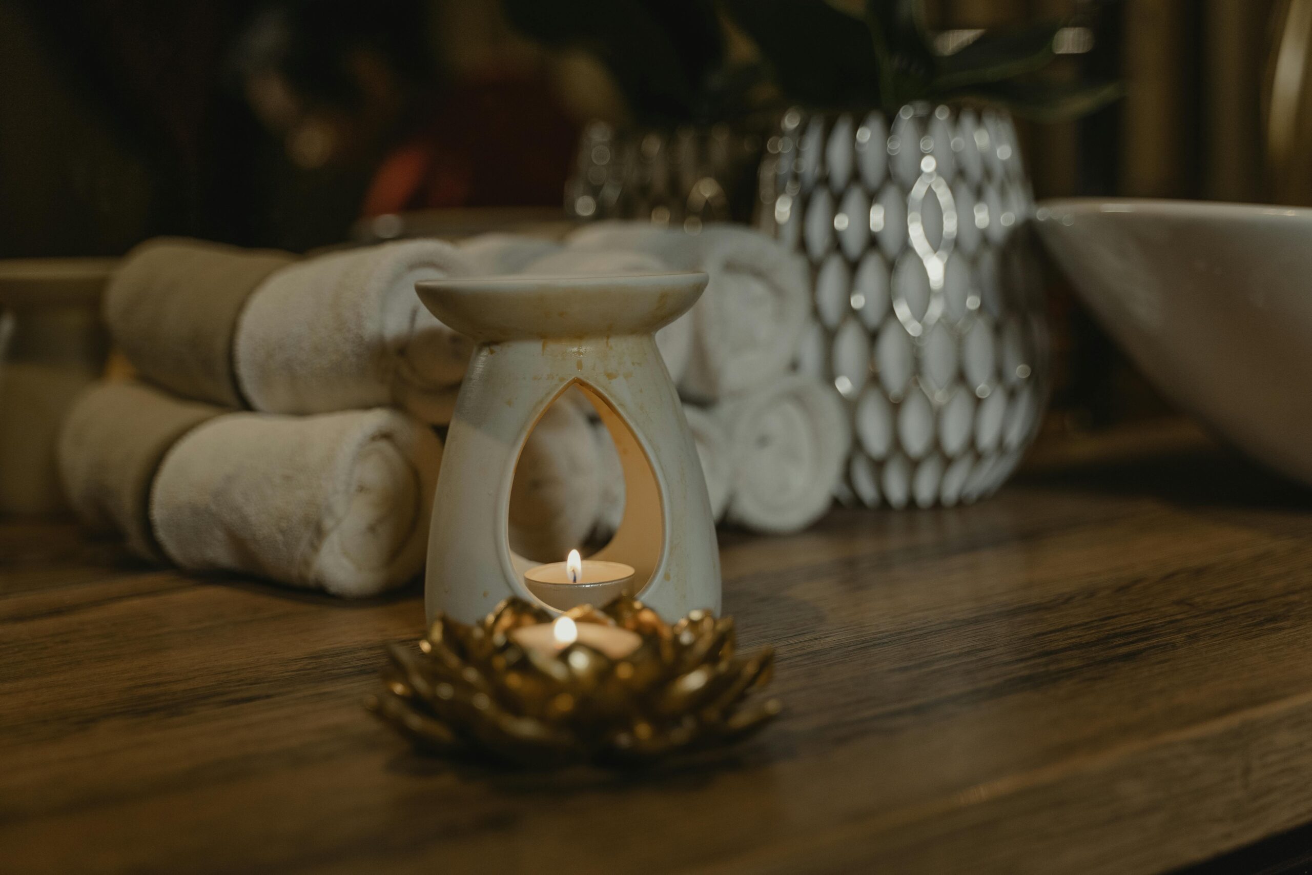 Serene spa setting with a lit candle, ceramic holder, and plush towels for relaxation.